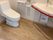 シンプルなデザインのトイレが設置されたスペースはとても広く、壁には可動式のバーや二連式のトイレットペーパーホルダーがある。