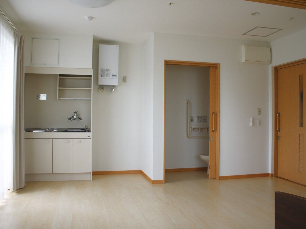 ブルーのユニフォームを着た男性スタッフと白い服を着た高齢女性が笑顔で体操をしている。