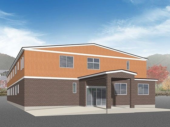 ブラウンとオレンジの2階建ての建物の周辺には自然が多く、建物の玄関部分には屋根が付いている。
