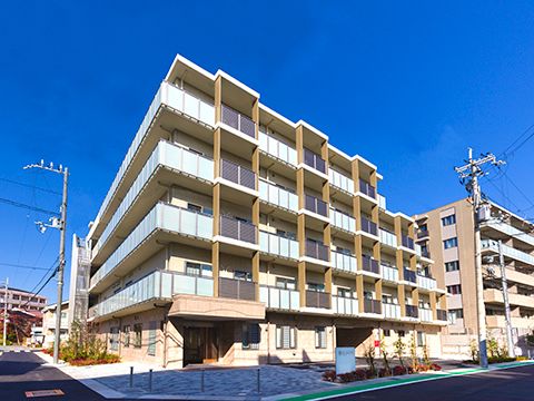 各フロアにベランダがある５階建ての建物は大きく、敷地内には緑も多く植えられている。