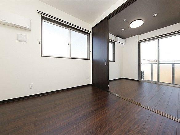 濃い色合いのフローリングを利用した居室の様子。広めのワンルームタイプの部屋