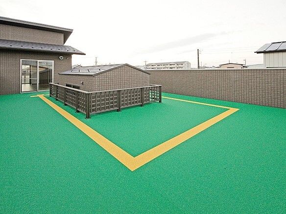 施設建物の屋上の様子。緑のシートが敷き詰められている屋上の写真