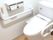 両サイドに手すりが設置されたトイレ。オレンジの呼び出しボタンが付き、トイレットペーパーホルダーは二連のものが付いている。