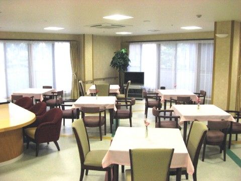食堂の壁は大きな一続きの窓になっており、明るい自然光を室内に取り入れている。食堂の一角にはテレビのほか、背の高い観葉植物が飾られている。