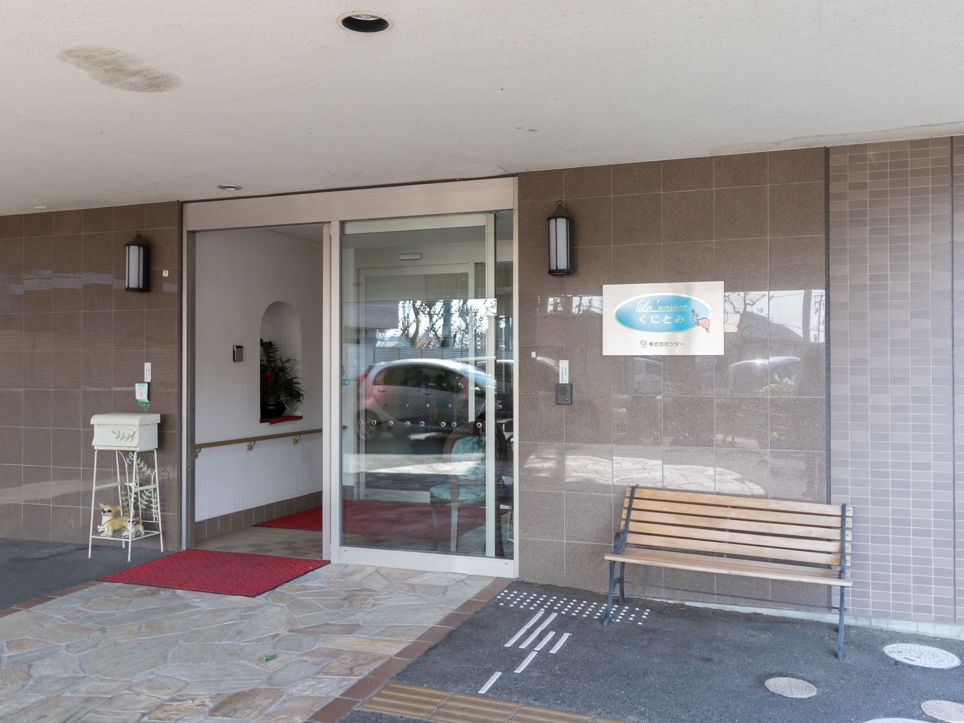 エントランスには自動ドアを設置して、入居者様がスムーズに通行できるようになっている。外にはベンチが用意されている。