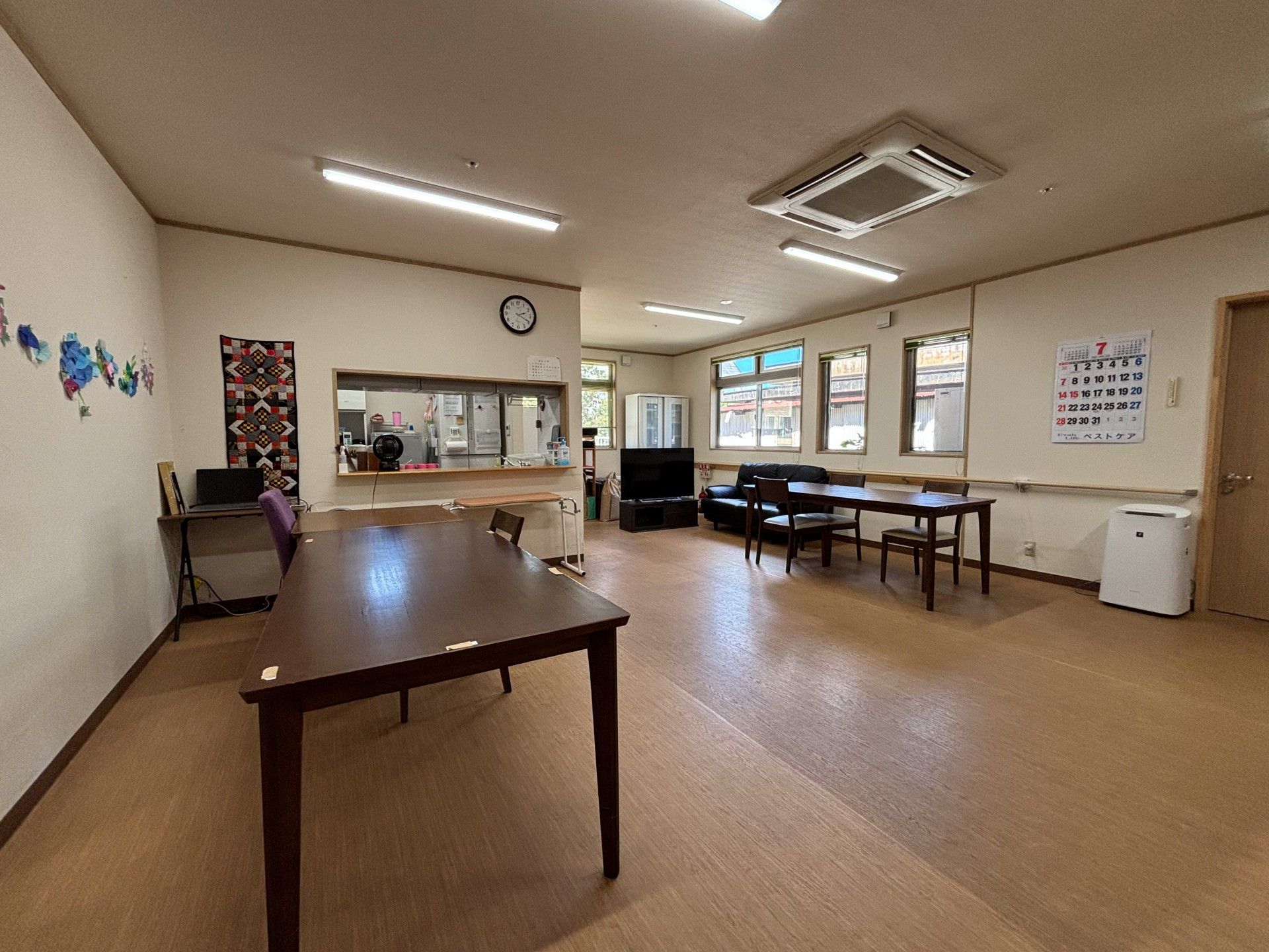 原っぱのような場所で笑顔で散歩をしている高齢女性のそばにはエプロンを付けた女性スタッフがいる。