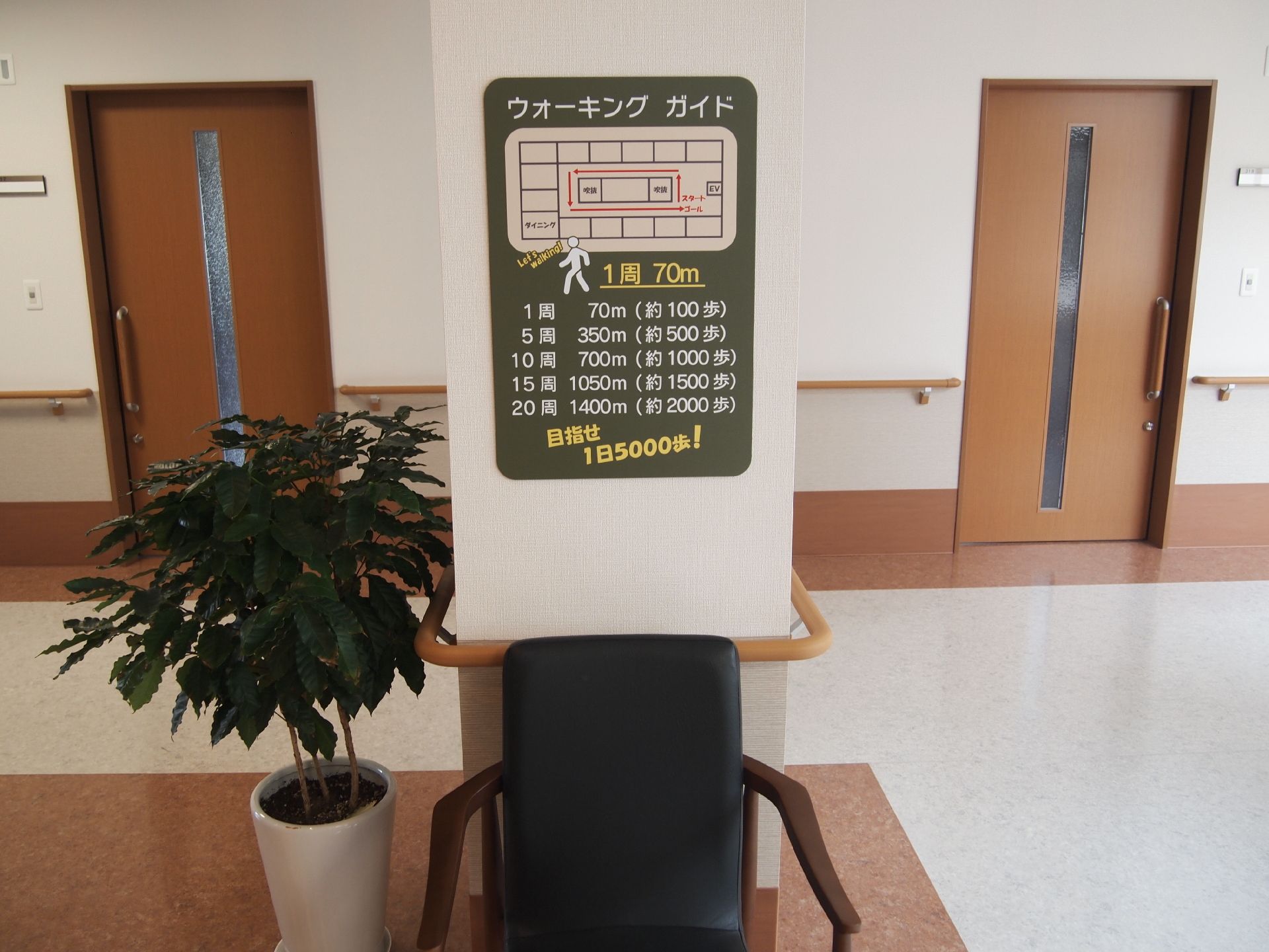壁に貼られたポスターには館内の廊下などの長さが細かく記されていて、そのポスターの下には黒い椅子が設置されている。