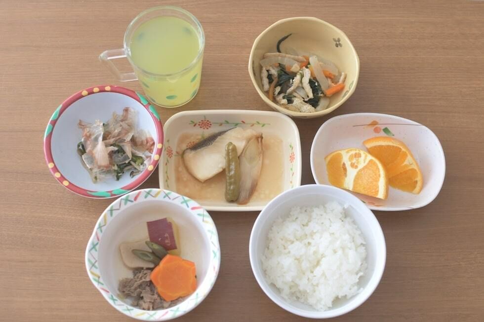 焼き魚とほうれん草のおひたしと、肉や野菜の煮物とカットオレンジのデザートが付いたメニュー