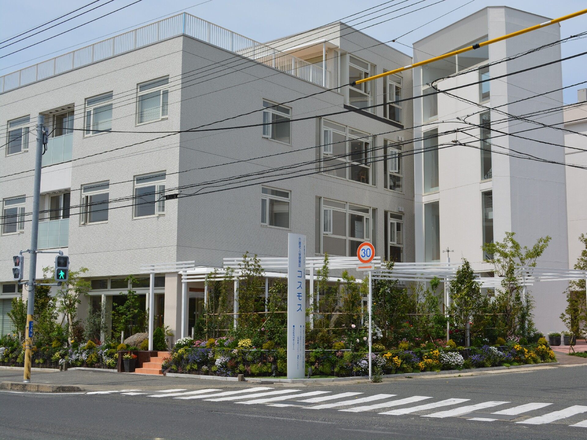 カメラ目線でほほ笑む男性。新聞を読みながらこちらを見ている様子。白いソファに座っている