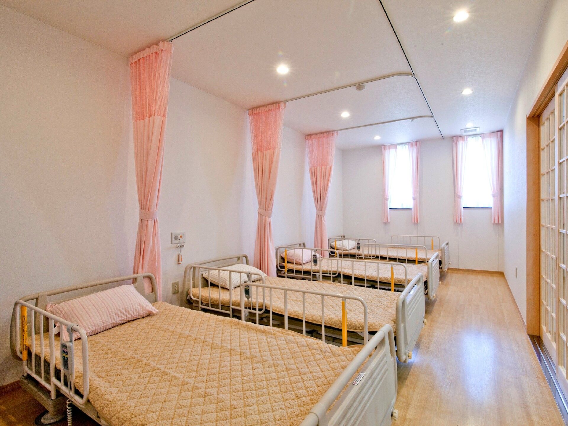 ピンク色のカーテンで仕切られている四つのベッドがある部屋