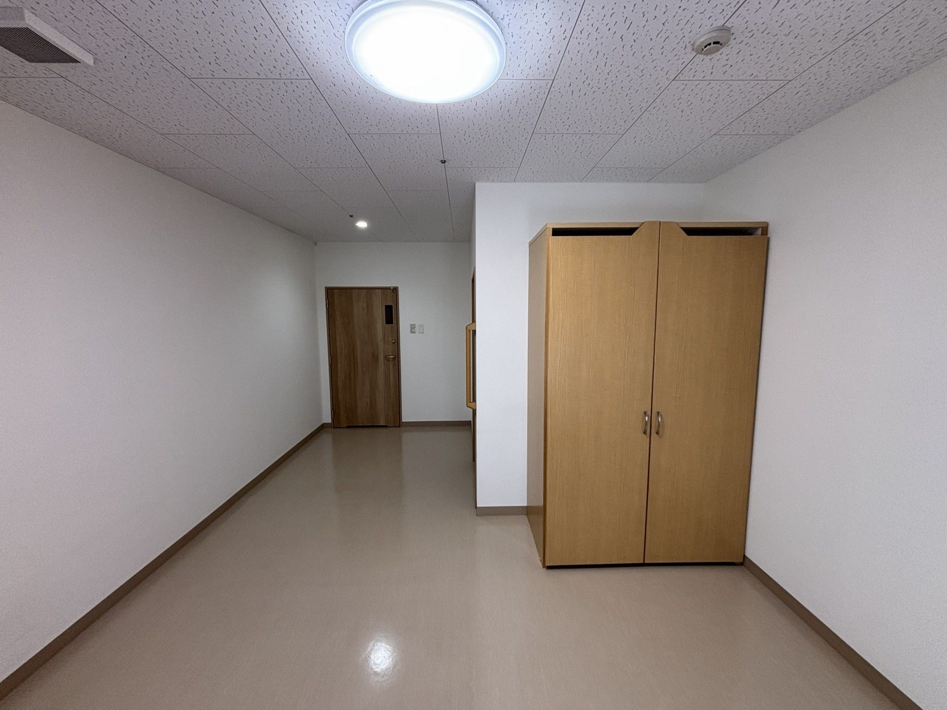 笑顔でサポートしている若いスタッフと福祉車両を降りようとしている眼鏡をかけた高齢男性。