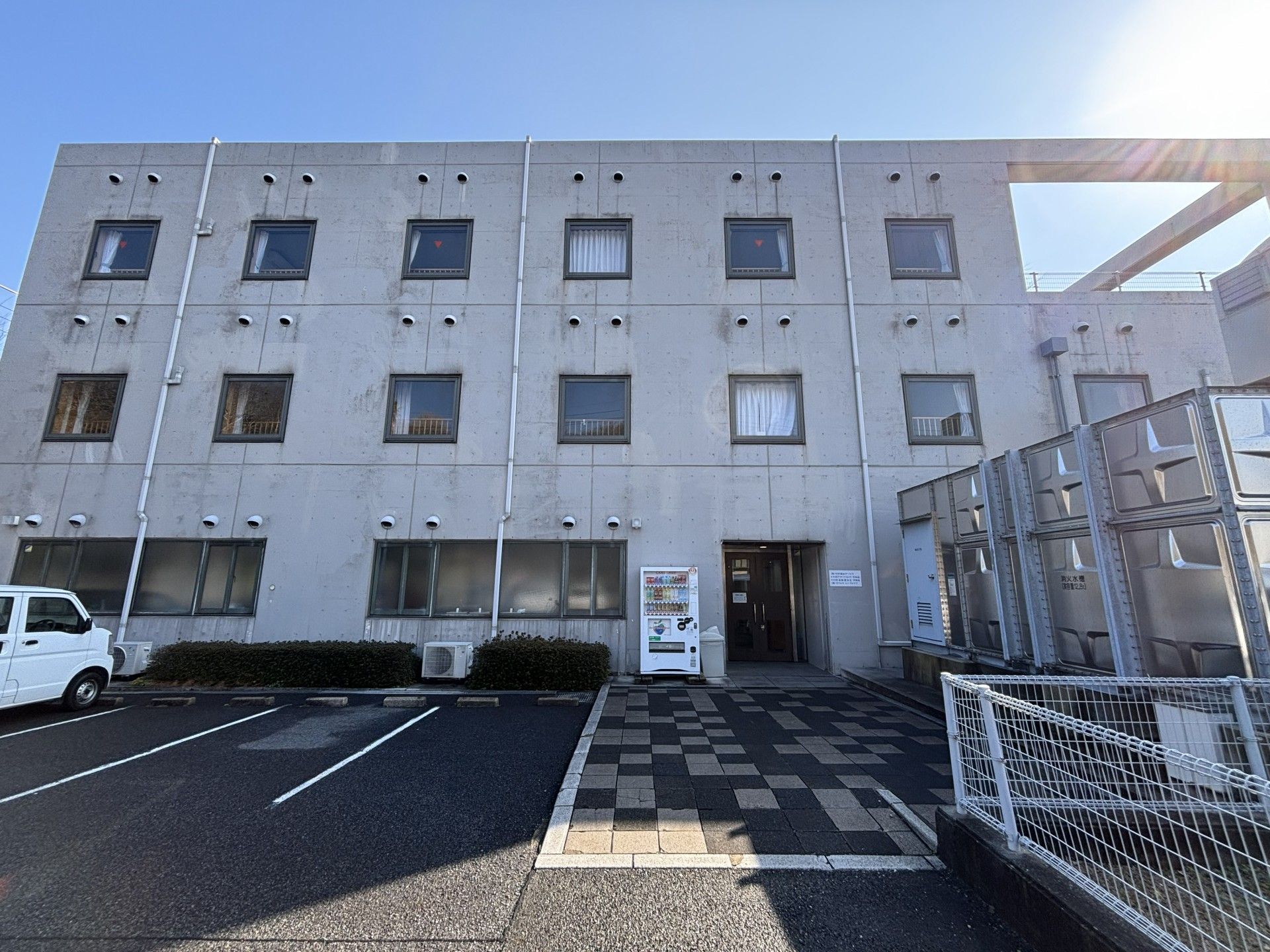 ジャケットを着た高齢女性と付き添いのエプロンを付けた女性スタッフ。笑顔で散歩している。