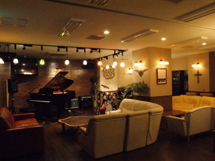 グランドピアノとドラム、ソファが置かれている薄暗い共有スペース