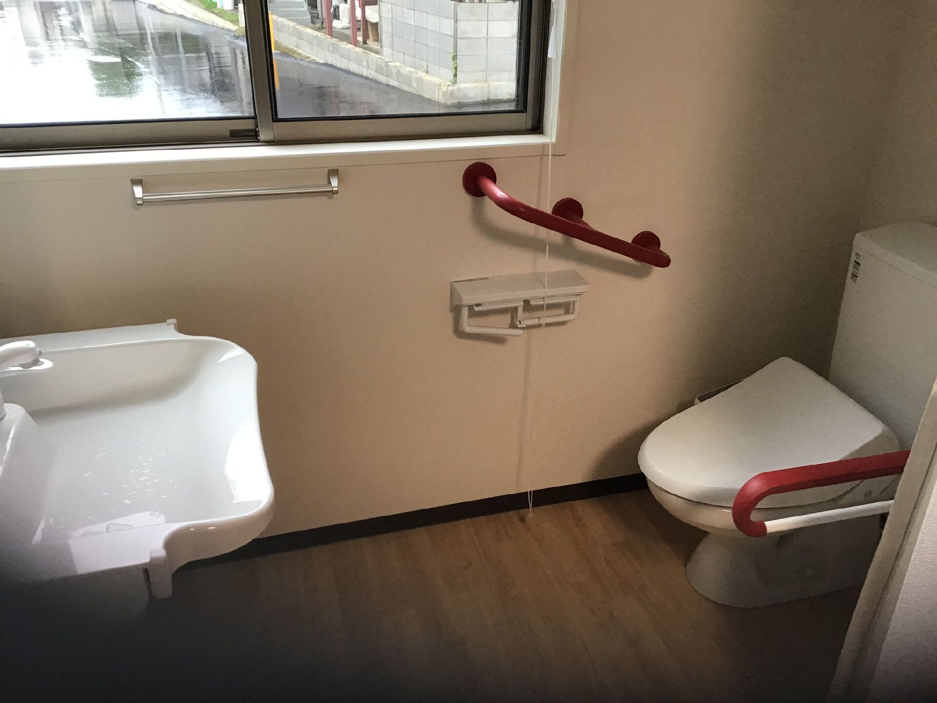 赤い手すりが付いたトイレにドアはなく、少し低い壁が設置されている。大きな洗面ボールが付いた洗面所もある。
