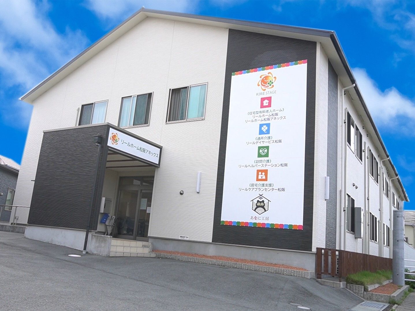 外出イベントを楽しむ車いすの男性入居者。エプロンを付けた女性スタッフが笑顔で付き添っている。