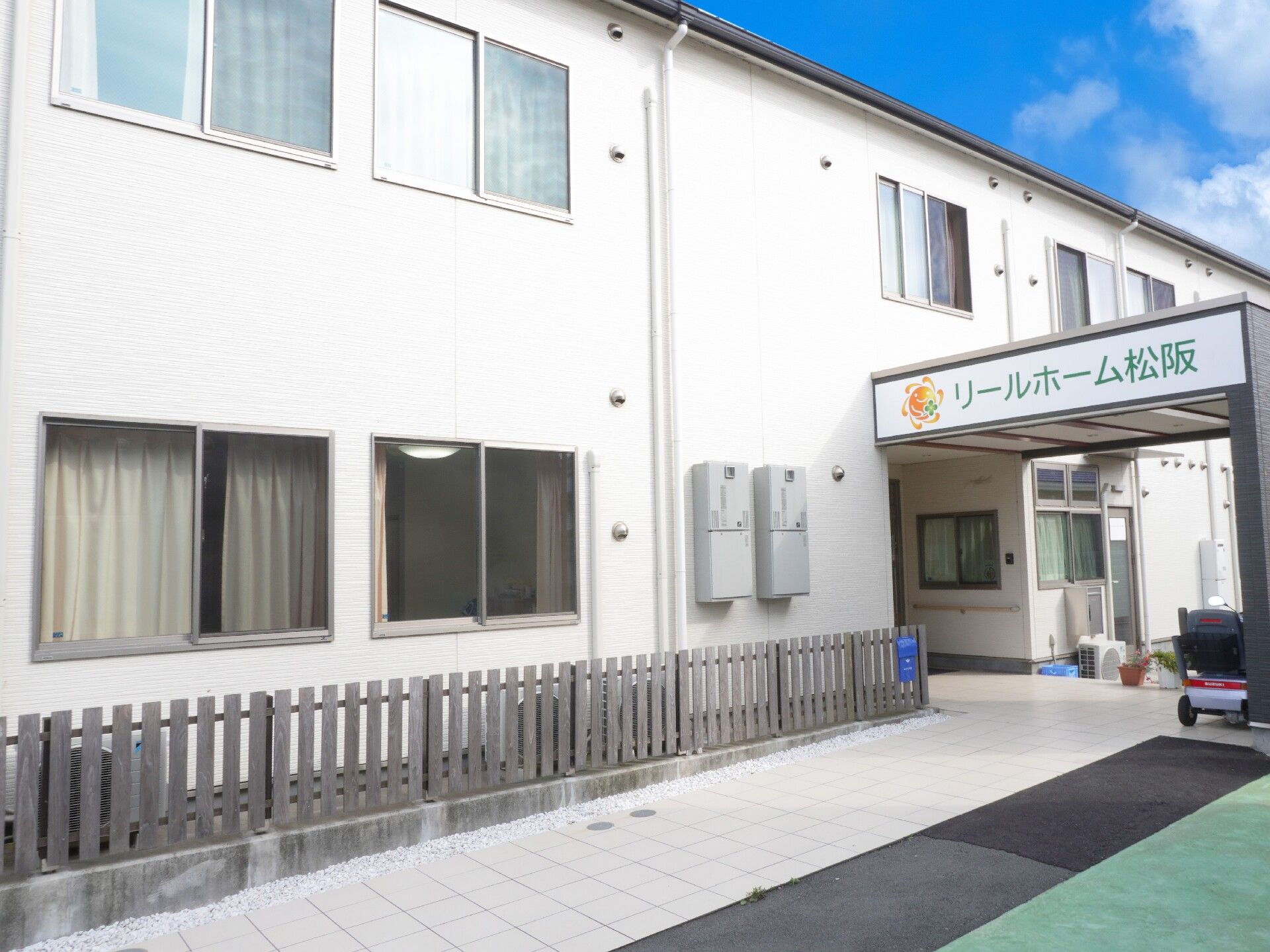 二階建ての白い建物が特徴で、1階玄関部分に屋根が付いている施設