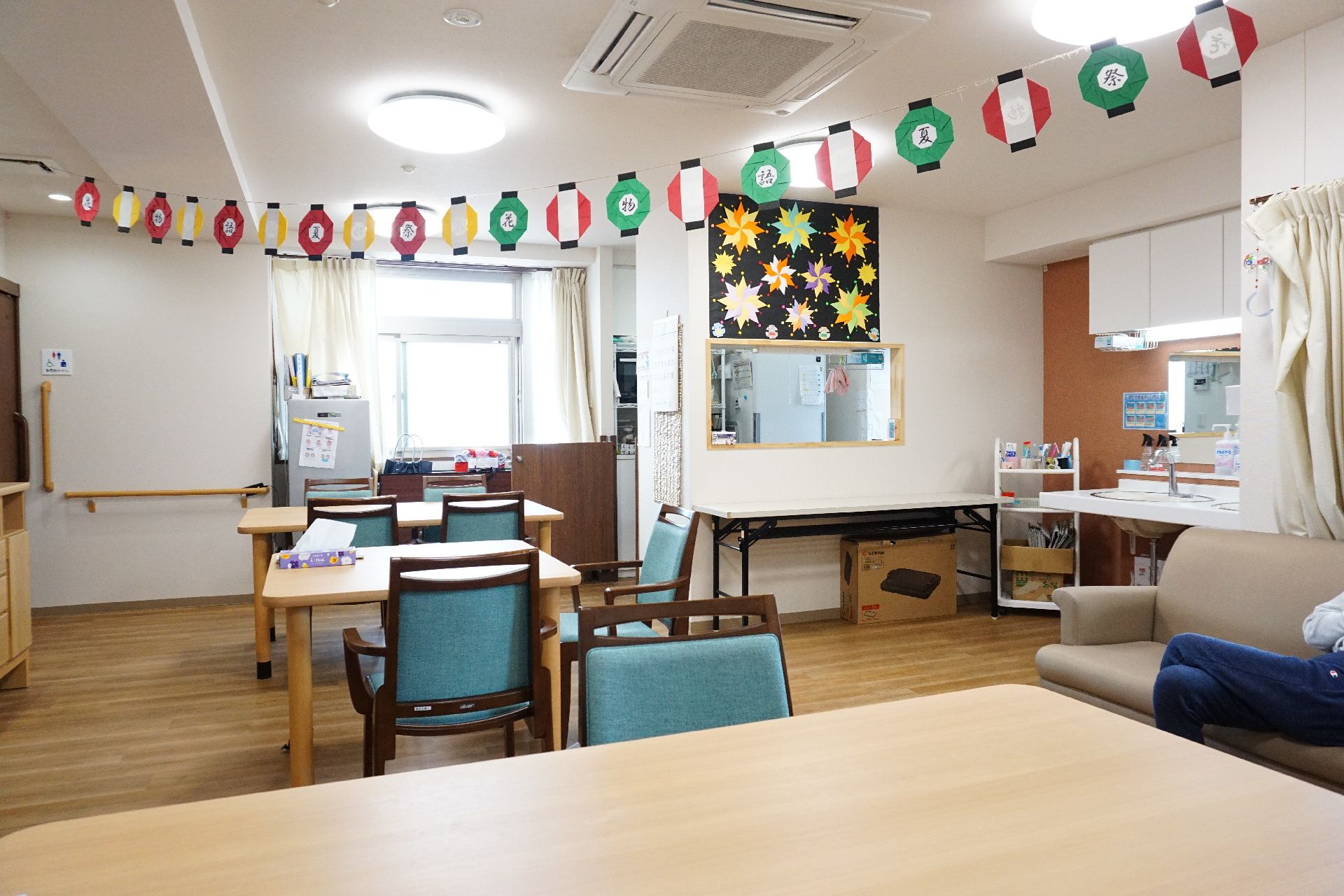 天井に提灯の絵が描かれた飾りがあり、テーブル・椅子が置かれているリビング