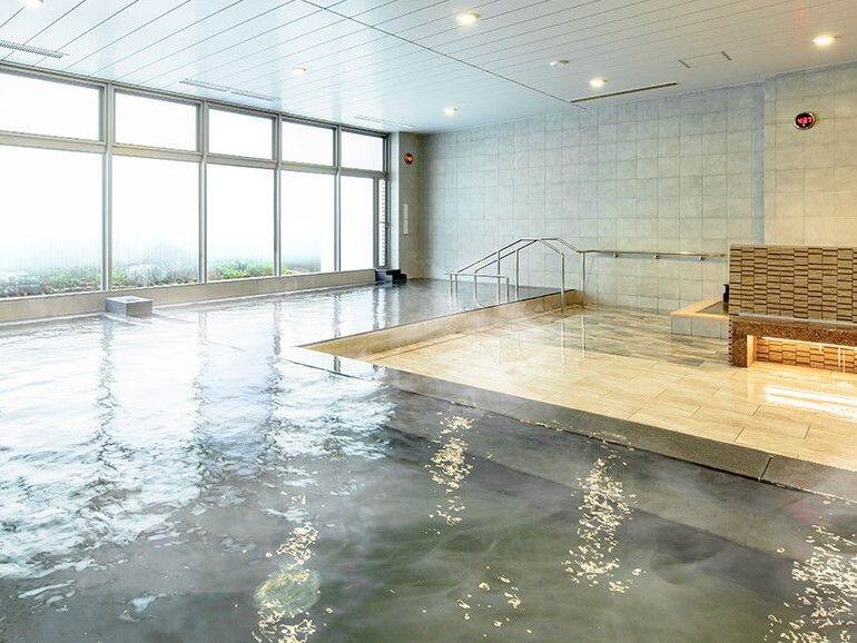 お湯がなみなみと入っている温泉浴室の様子。手すりがついたプールのような形