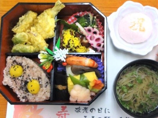 お膳にきれいに盛られているハレの日のメニュー。お吸い物とデザートもある