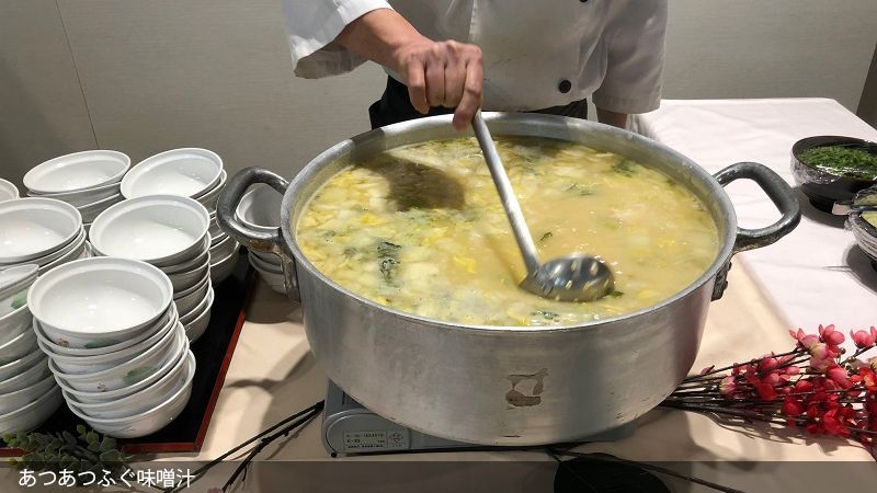 大鍋の味噌汁を玉杓子でかき混ぜる様子