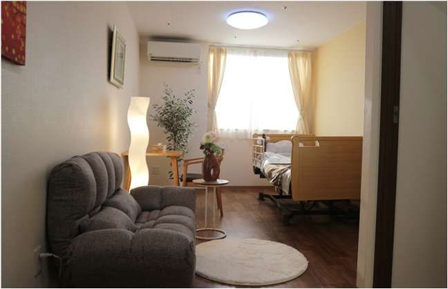 三角屋根が付いた3階建ての建物はブランとベージュで玄関には車寄せが付き、周辺には緑が多くあり、落ち着いた雰囲気。