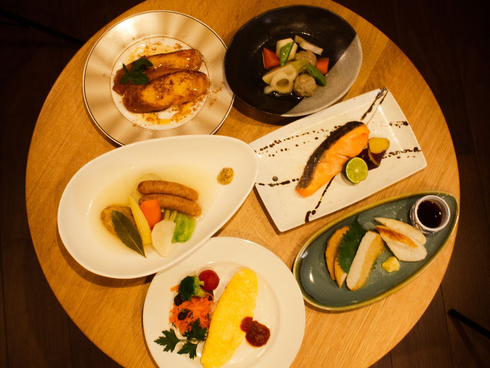 オムライスやポトフ、焼き鮭や野菜の煮物が並んだデーブル