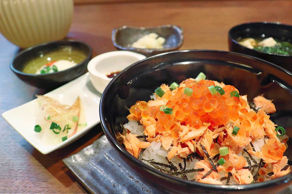 鮭フレークといくらの丼ぶりと味噌汁がセットになった献立