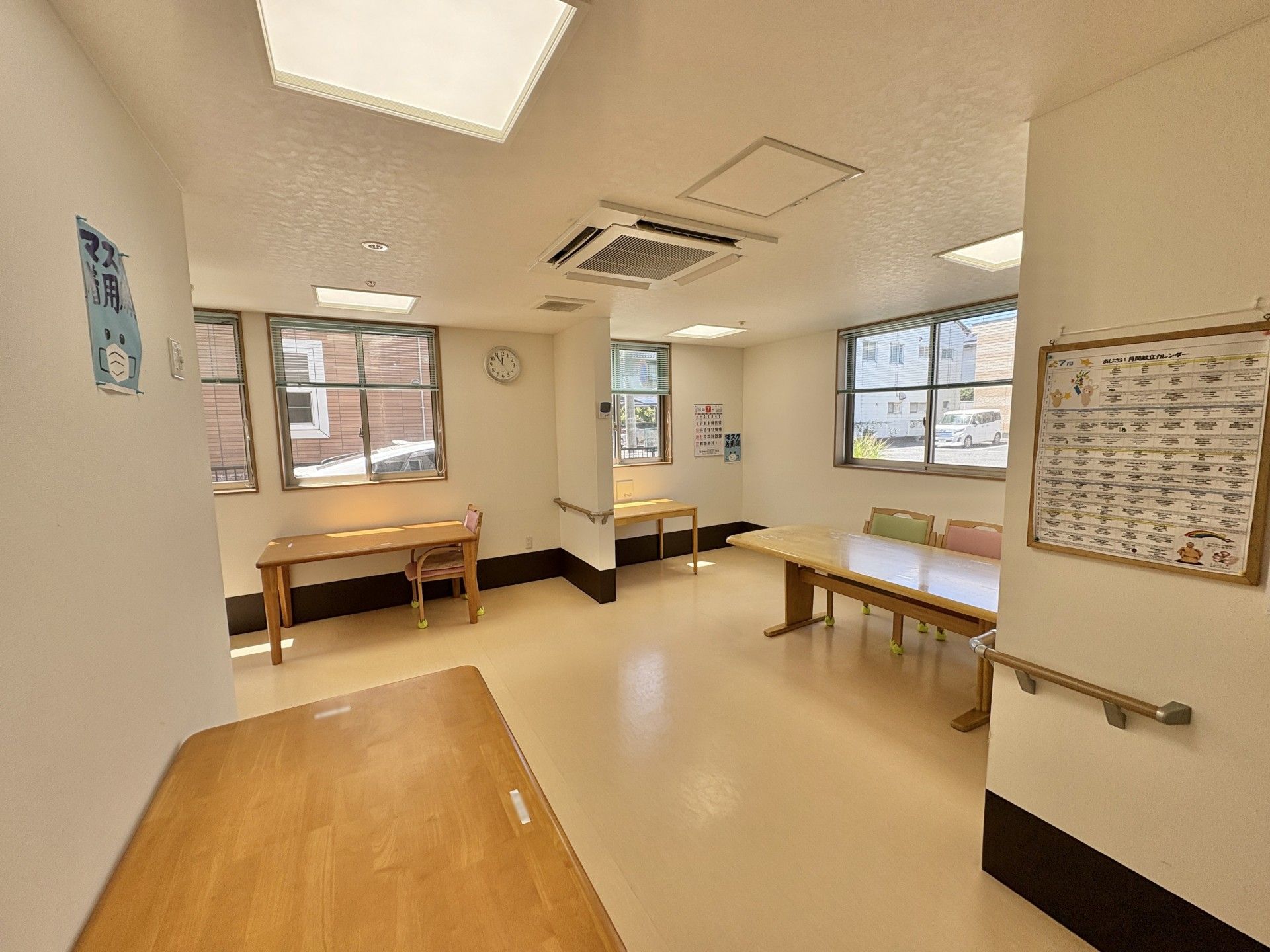 ピンクのエプロンを付けた若い女性スタッフとカーディガンを着た高齢女性が笑顔で過ごしている。