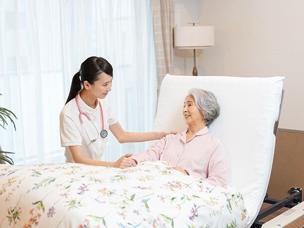 薬を飲む高齢女性と付き添いの女性ヘルパー