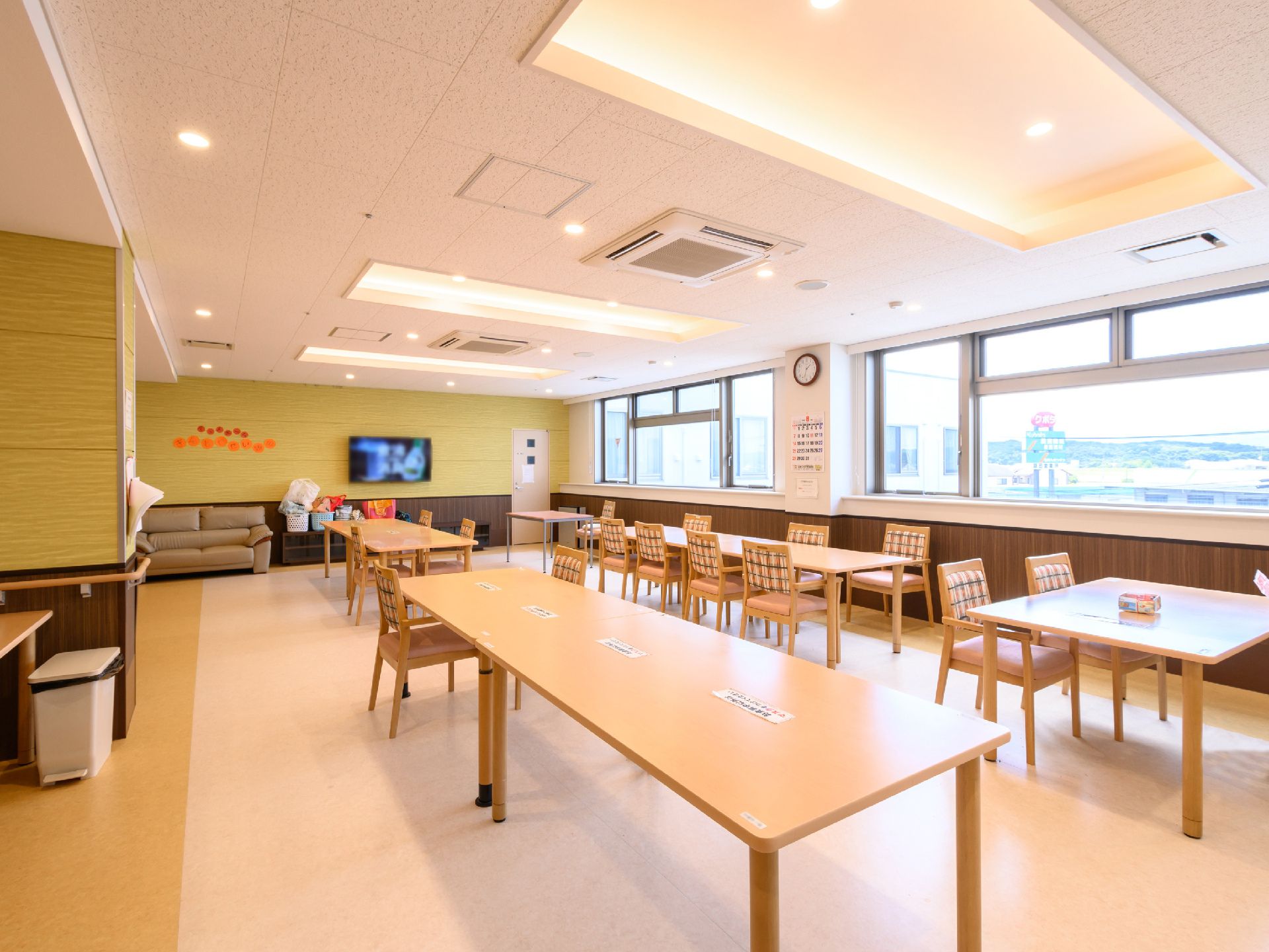 木製の机が並んだ壁１面が窓ガラスになっている広間
