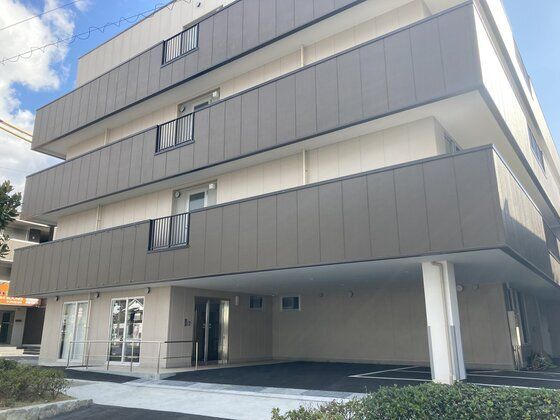チェックのパジャマ姿でベッドに横になる高齢の女性の介護に当たる女性スタッフ。