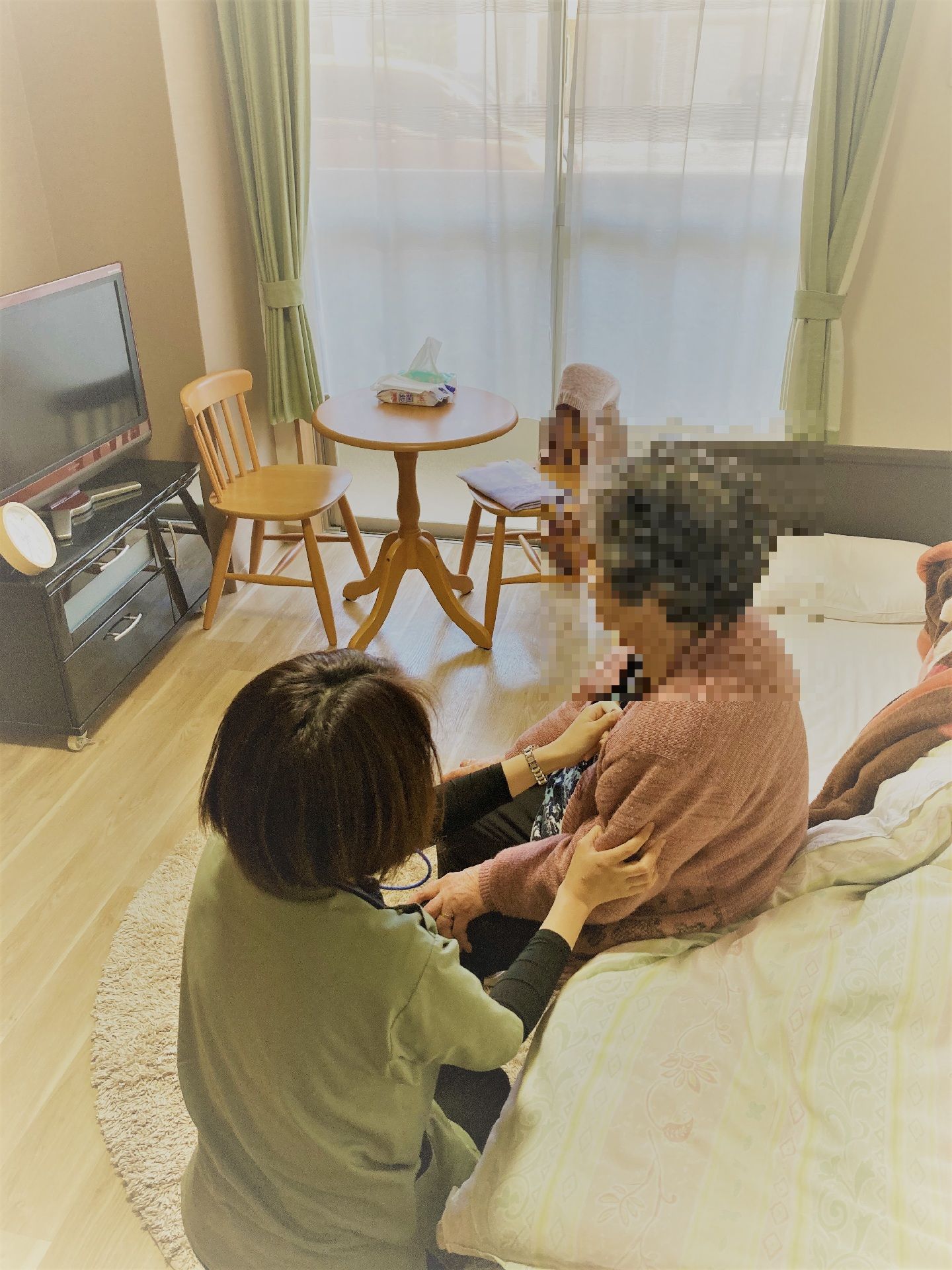 ベッドに座っている高齢女性の介助をする女性スタッフ