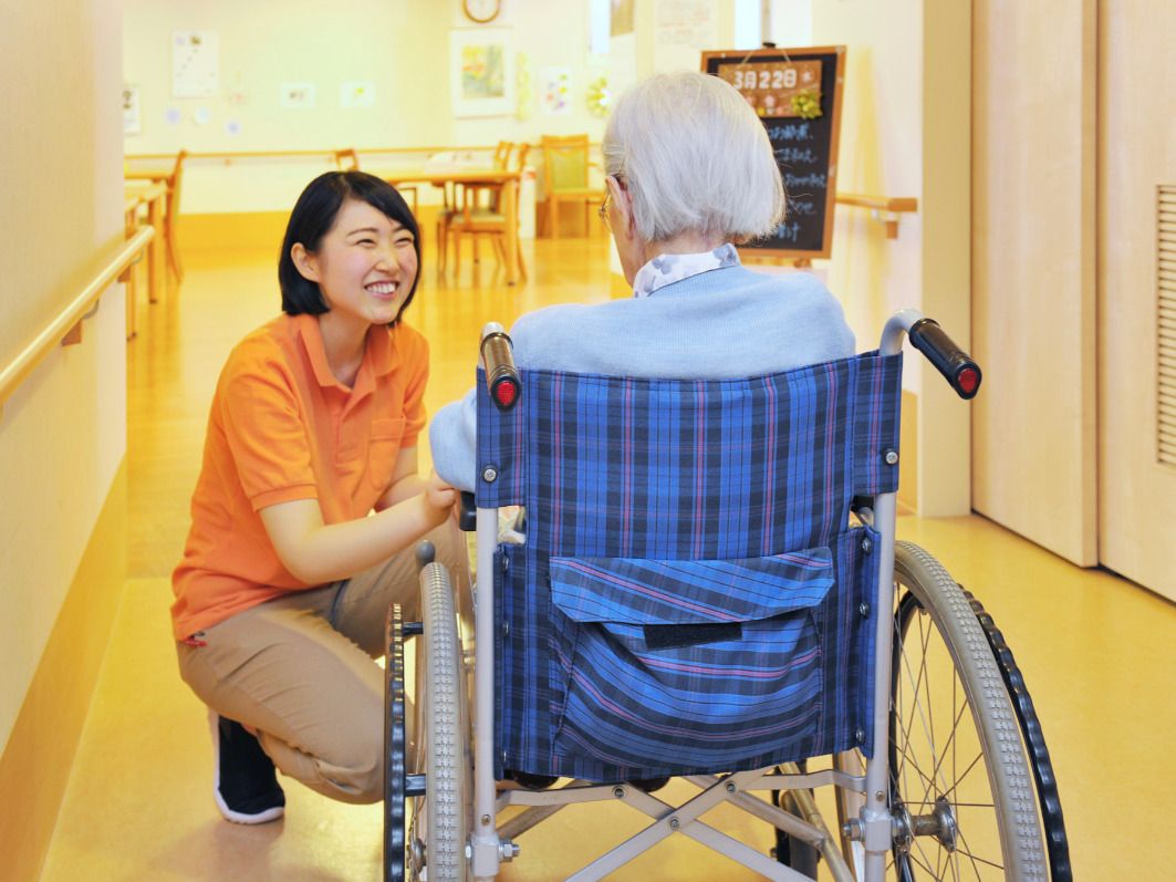 車椅子に乗った男性に目線を合わせ、笑顔で話しかける女性スタッフ