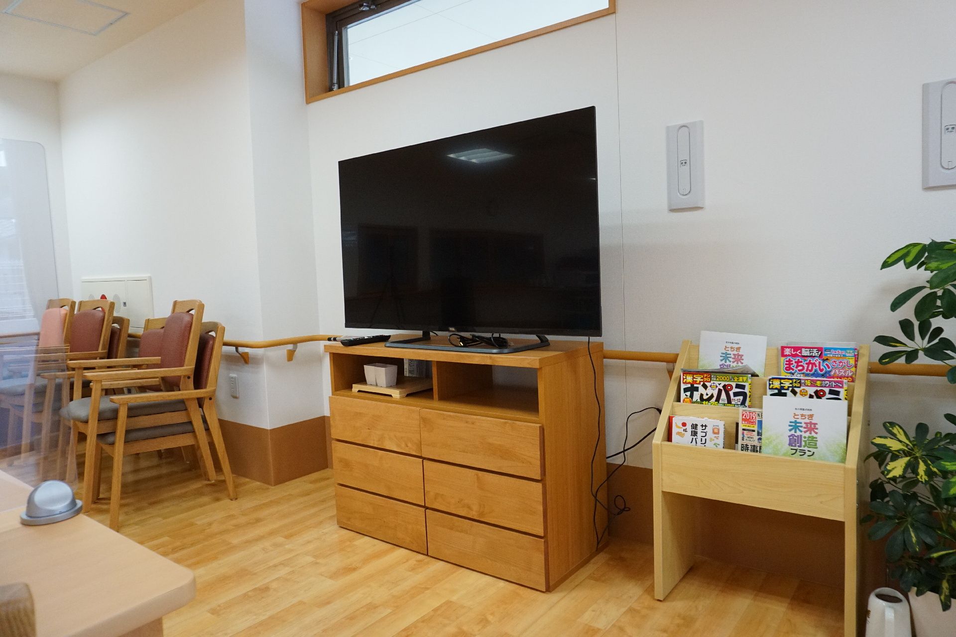 大きなテレビが設置され、雑誌の入っているラックもあるリビング