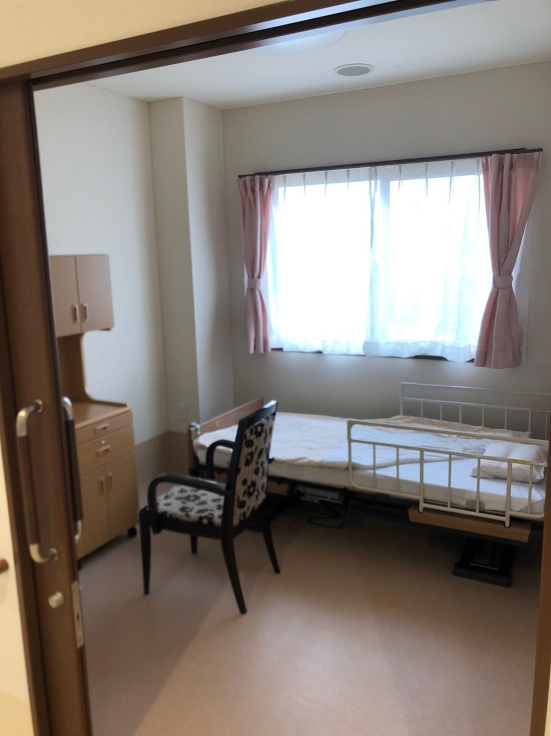 日当たりのいい場所で話している女性スタじょと高齢女性。スタッフはカルテのようなものを持ってペンで書き込みをしている。