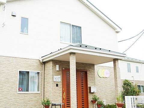 玄関の周辺にはプランターがたくさん置かれ、明るい雰囲気。1階部分はレンガ調の壁、2階部分は白。