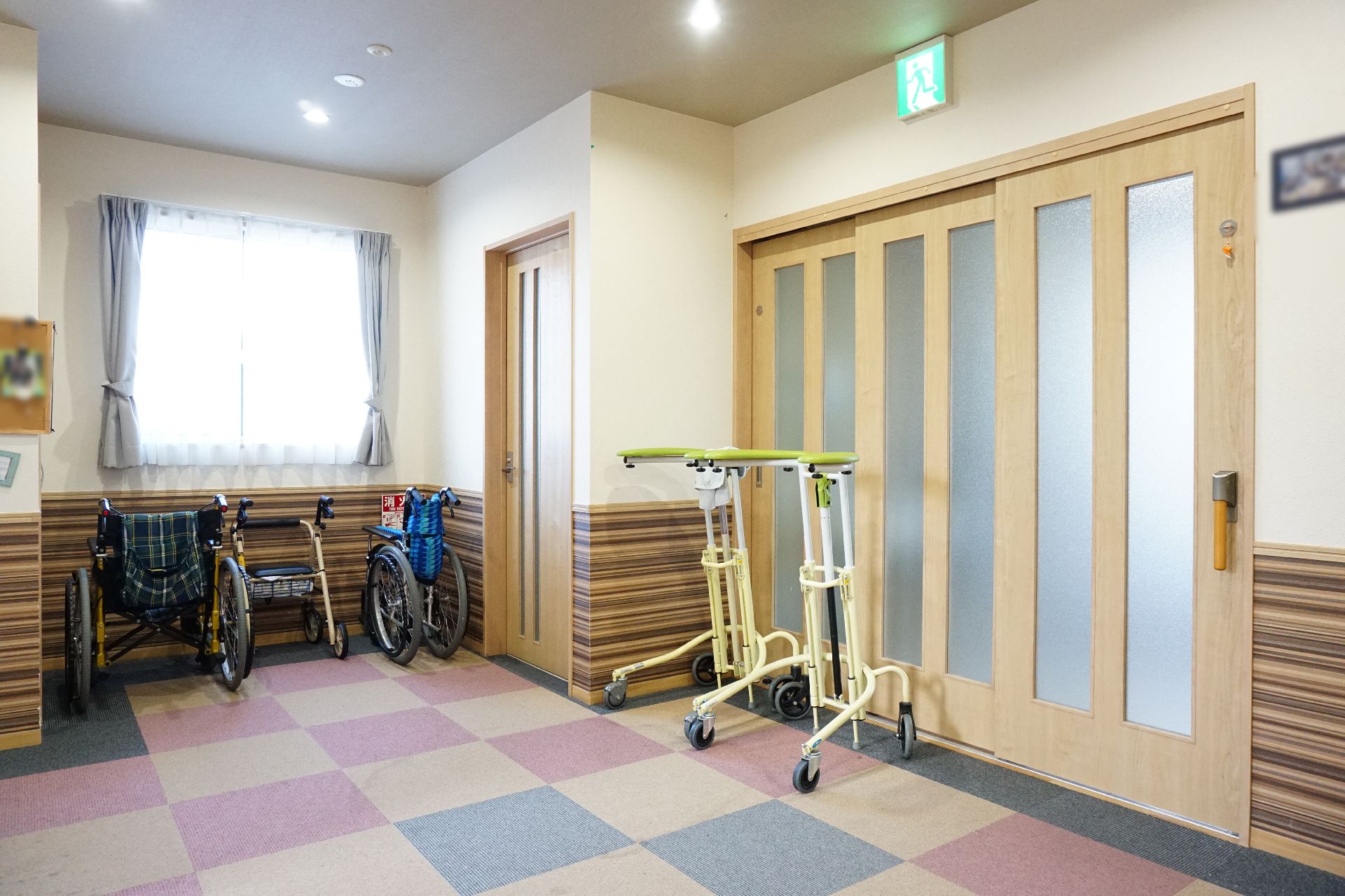 日差しの指す、手すりが設置されたスペースのある廊下