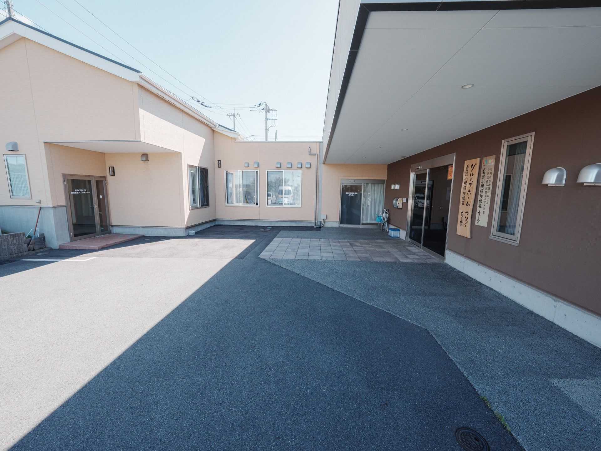 なにかを見て笑顔で手をたたいている高齢女性とスタッフの様子。施設での一場面の写真