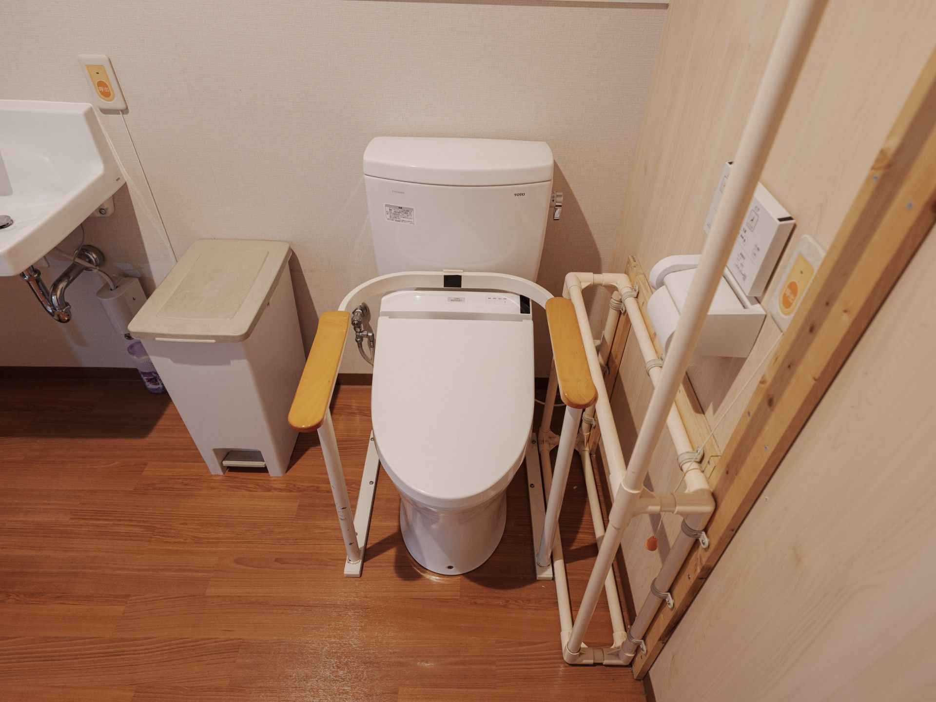 車いすに乗る高齢者が笑顔で手を振っている様子と車いすを押している介護スタッフ