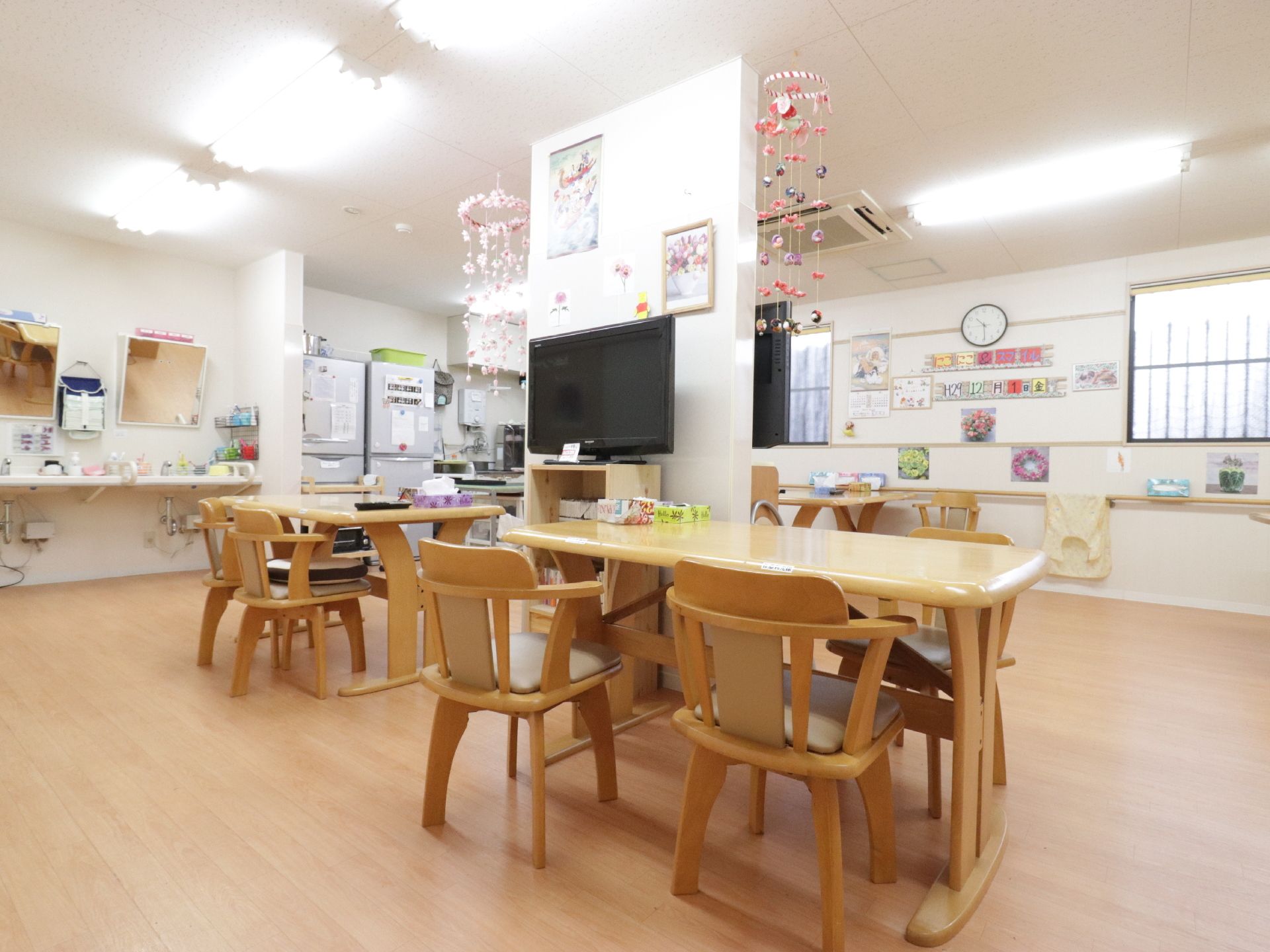 部屋の中央にテレビが設置してあり、そばにテーブルと椅子が置いてある。奥には冷蔵庫やキッチンがあり、その横には洗面台が２つ設置されている。