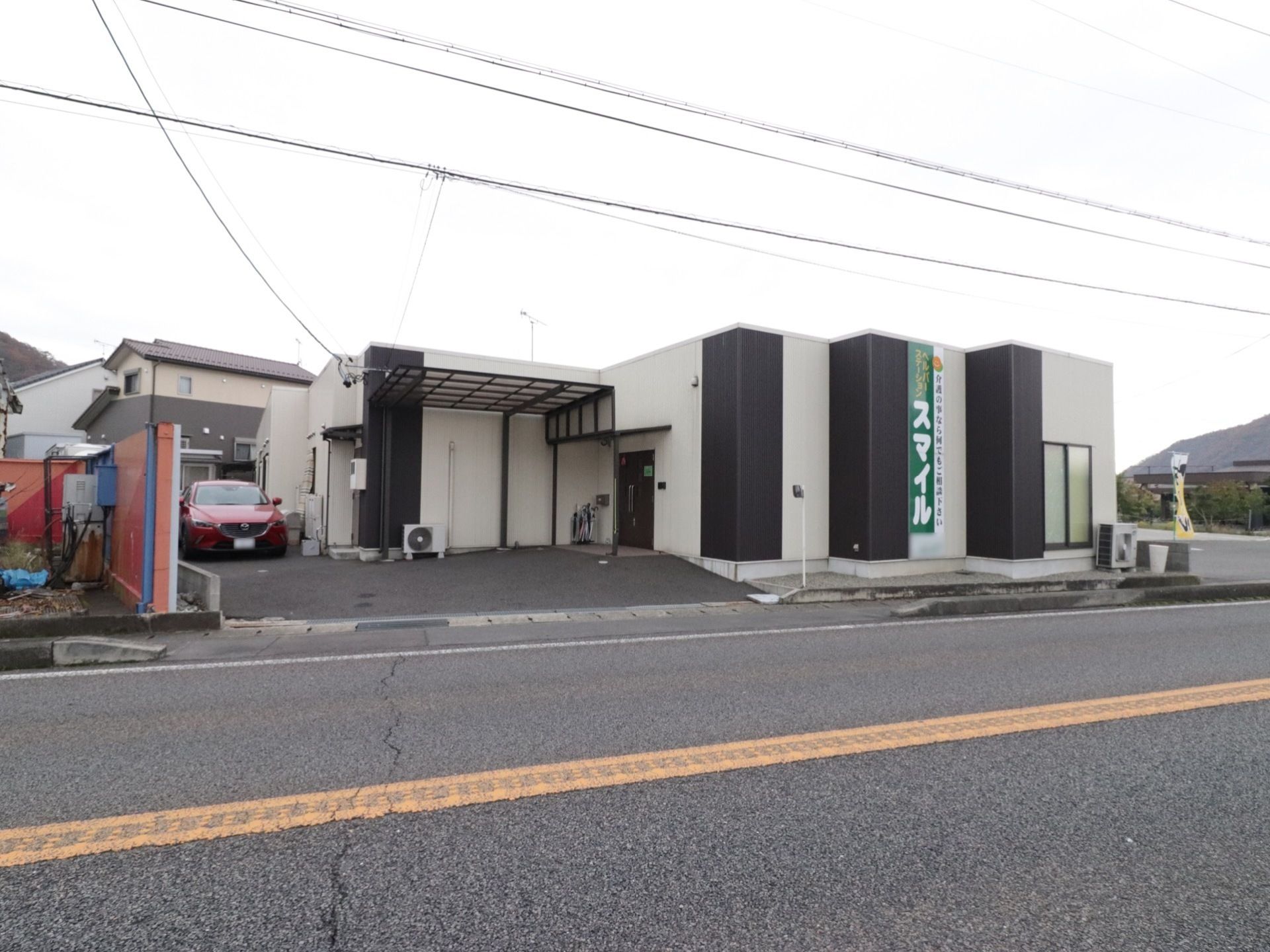 施設は道路に面している。白と黒の壁になっていて、大きく施設名も書かれている。施設の横に駐車場も完備されている。