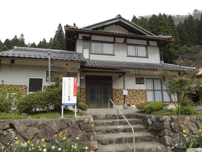 2階建ての建物は純和風な造りで、瓦屋根が付き、1階部分よりも2階部分が小さい。周辺には緑が多く、玄関前の階段には手すりがある。