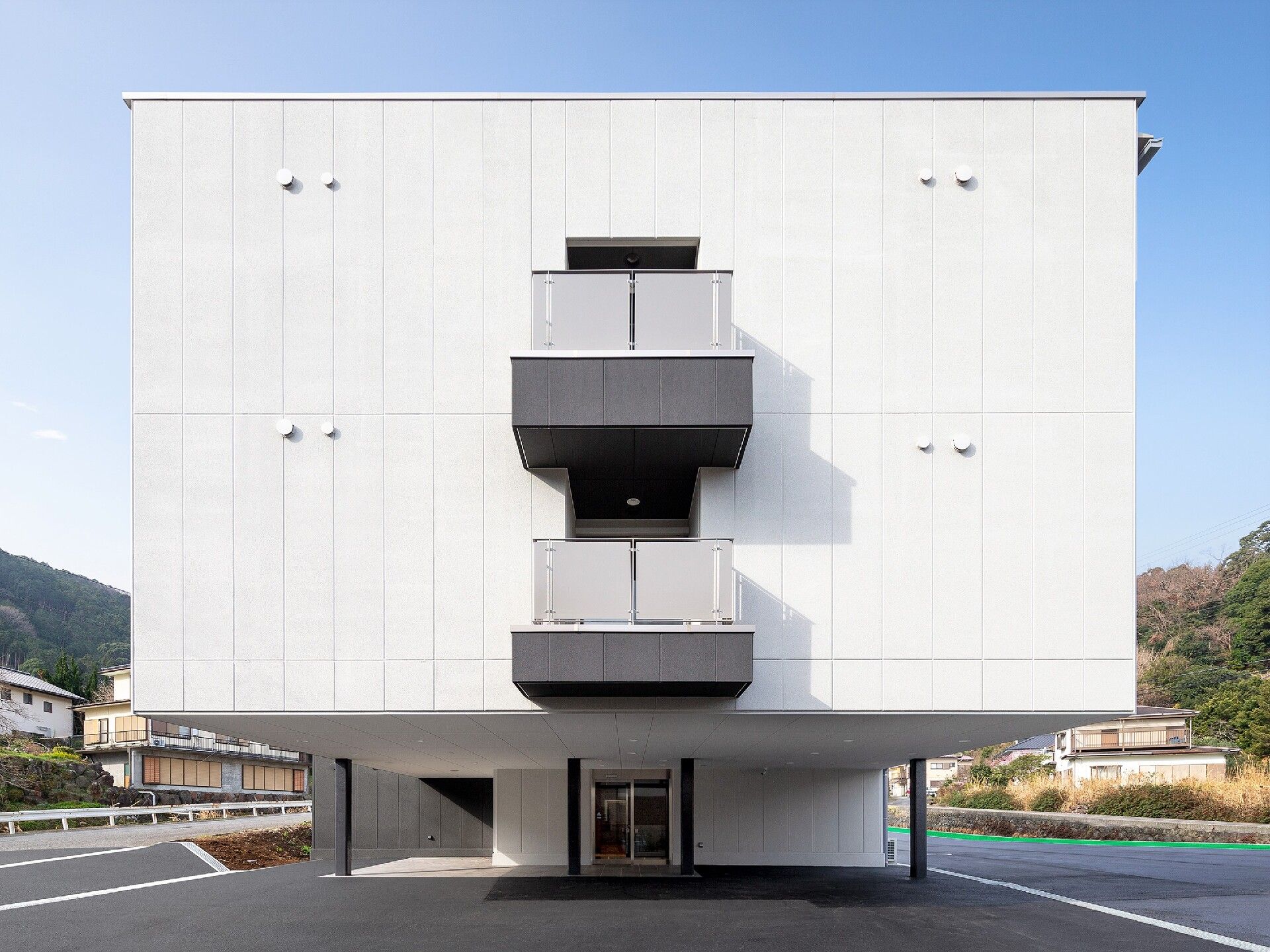 建物の側面が玄関になっていて、玄関部分が少し奥に入っていることで上のフロアが屋根の役割をしている。