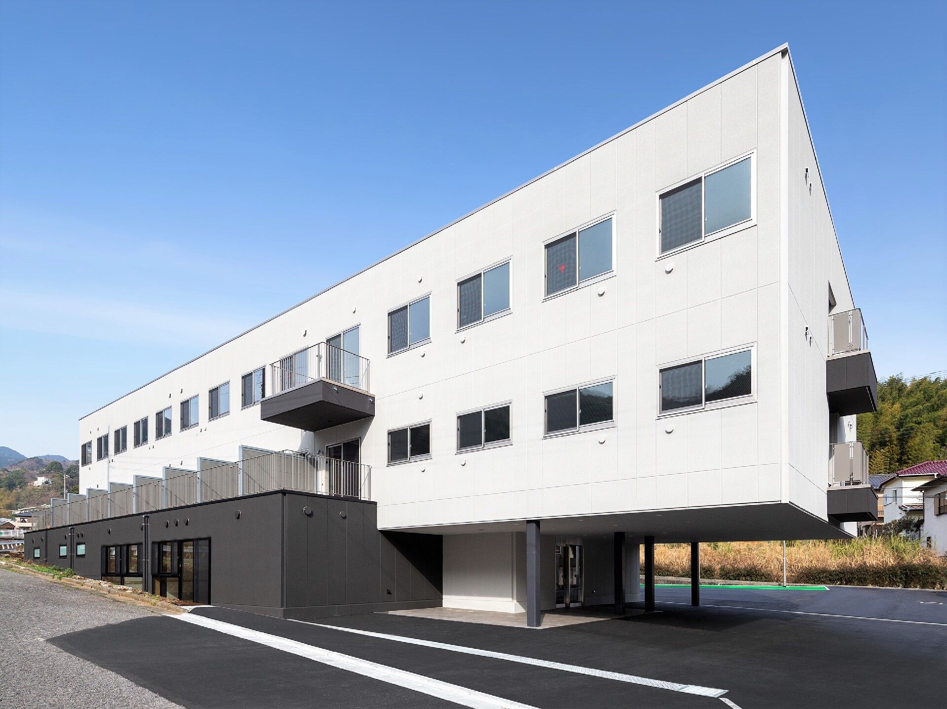 白い３階建ての建物には窓がたくさんつき、テラス付きの居室もある。