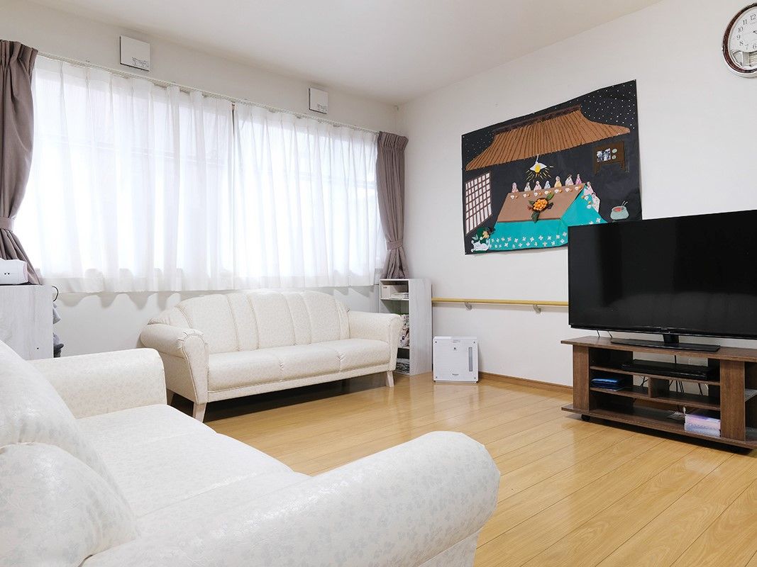 2組の白いソファーと大型テレビが設置されているリビング
