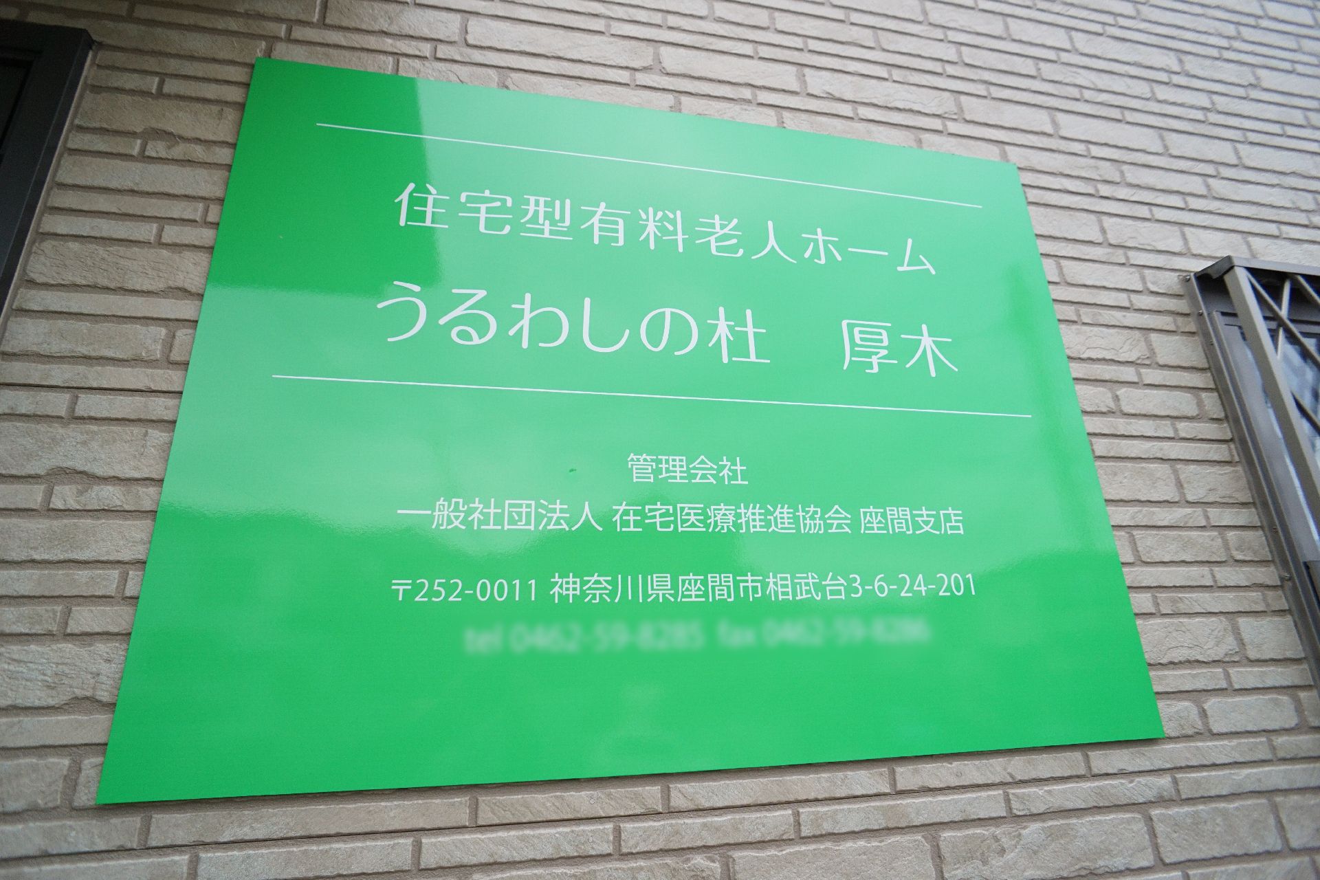 なにかを見て笑顔で手をたたいている高齢女性とスタッフの様子。施設での一場面の写真
