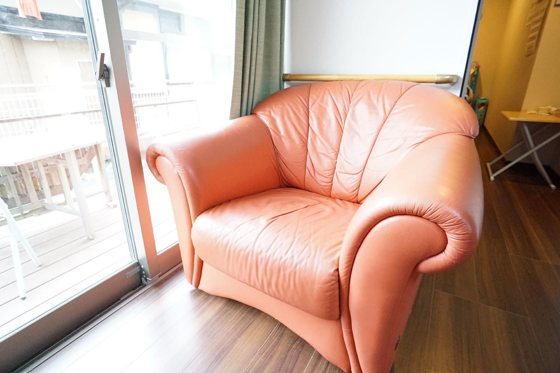 自然豊かな場所を車いすで散歩している高齢男性とそれを補助しながら話している女性スタッフ