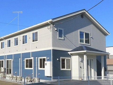 2階建ての建物の周りにはフェンスがあり、植物も植えられている。玄関部分には屋根が付き、段差もない。