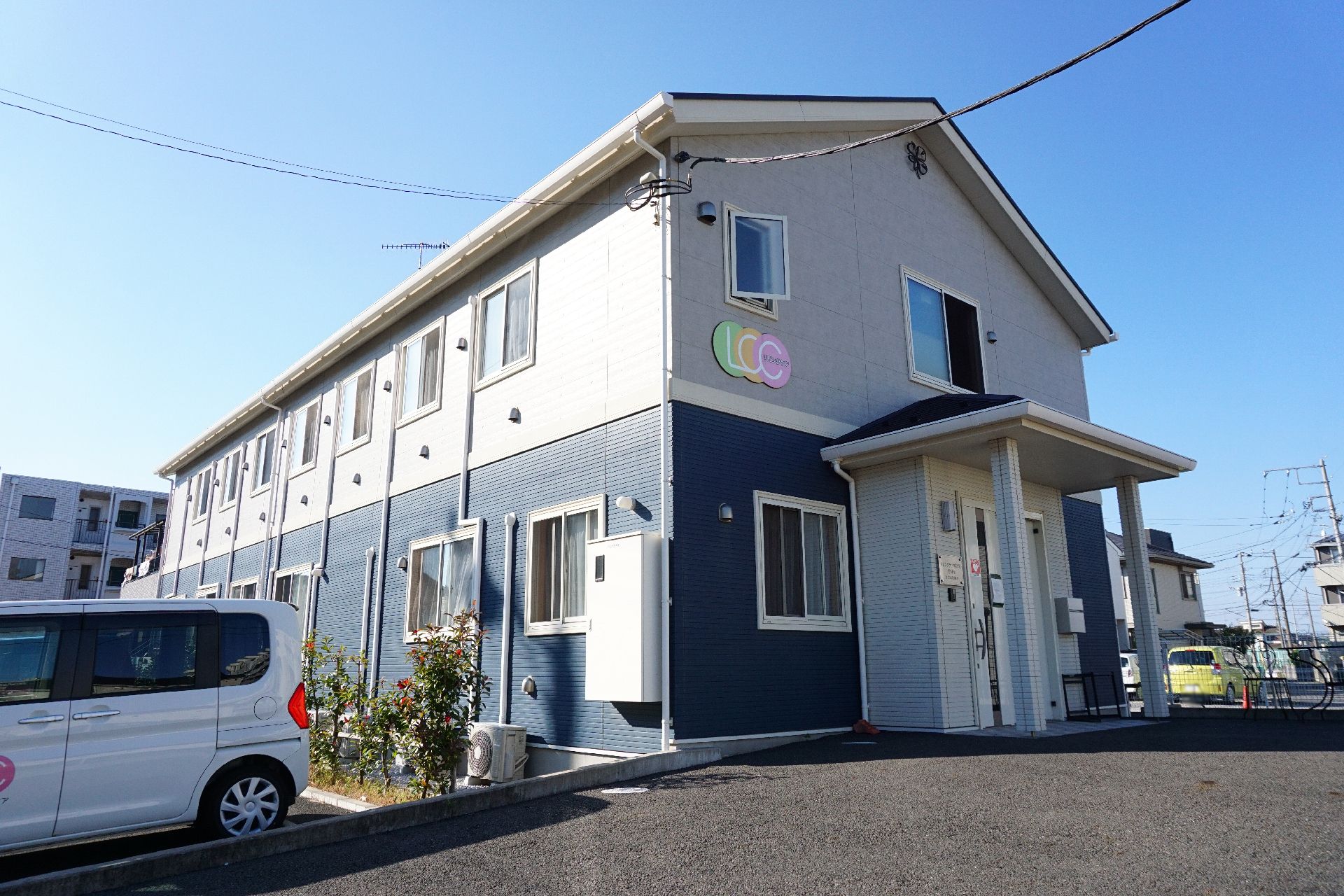 白と紺を基調とした３階建ての介護施設の外観