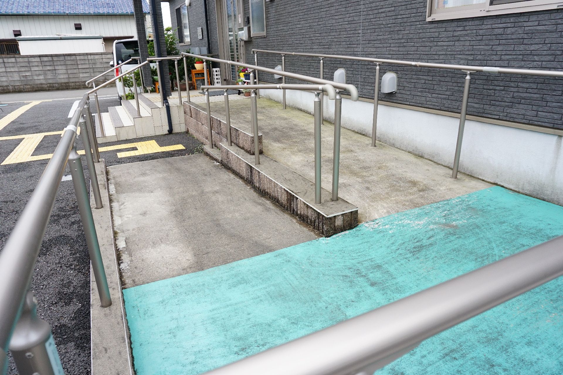 車椅子の人のために手すりとスロープが設置された介護施設の玄関